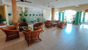 A spacious lobby with wicker furniture, stone walls, and ceiling fans. - Virgo Batik Resort Teluk Batik Lumut (Lumut)