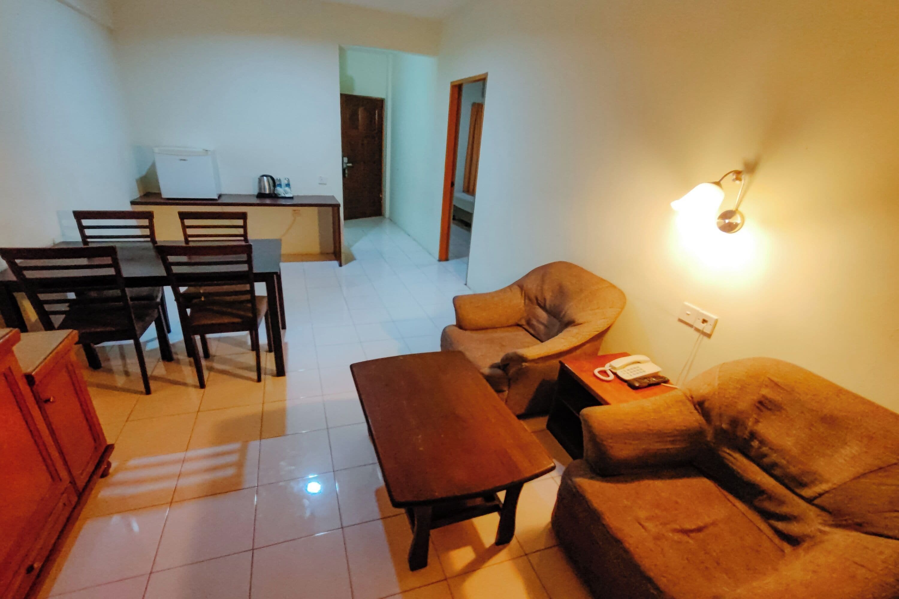 A living room with a sofa, a wooden coffee table, and a dining area with a table and chairs.