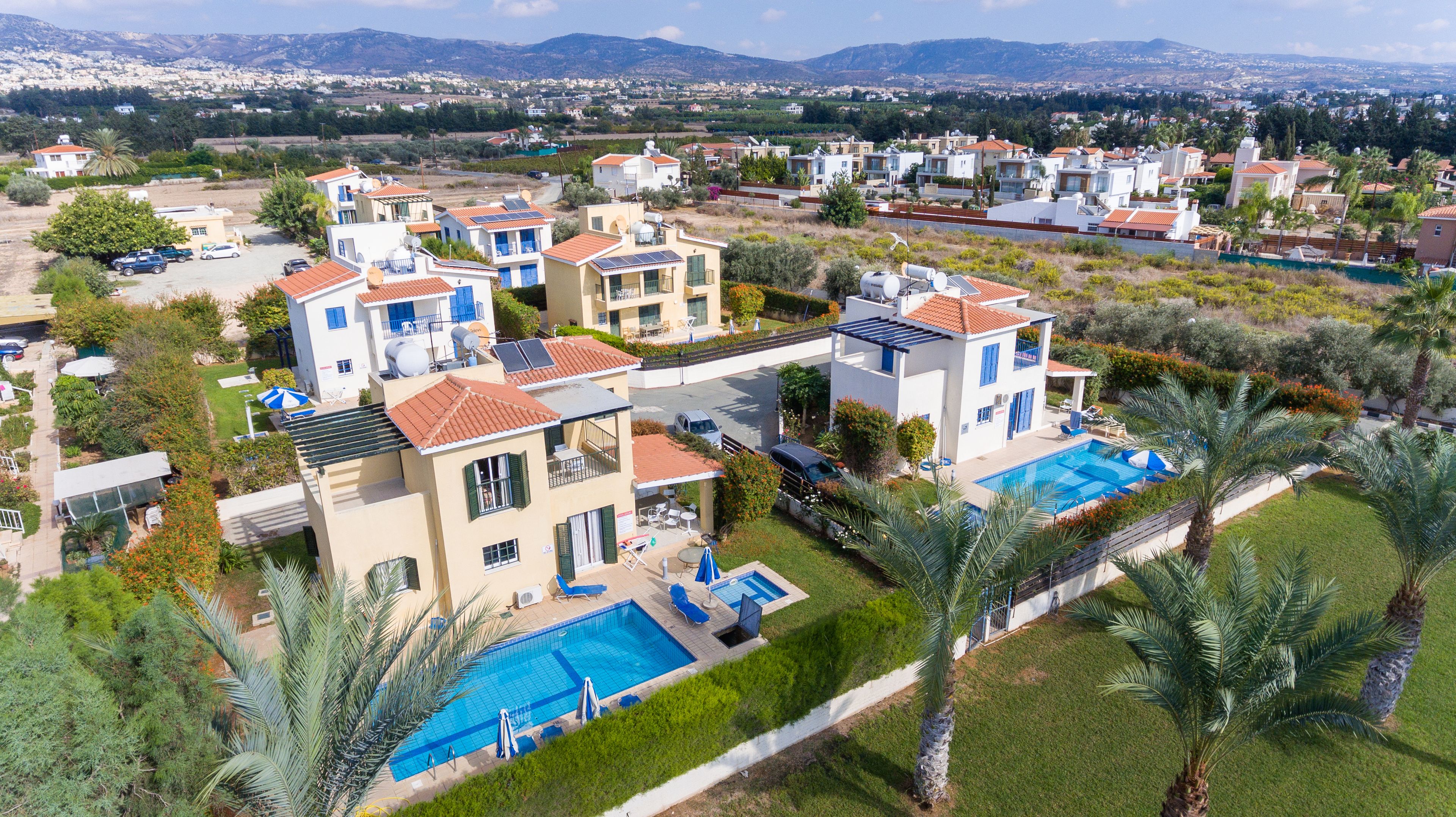 A residential area with modern houses, a swimming pool, and a view of the surrounding landscape.