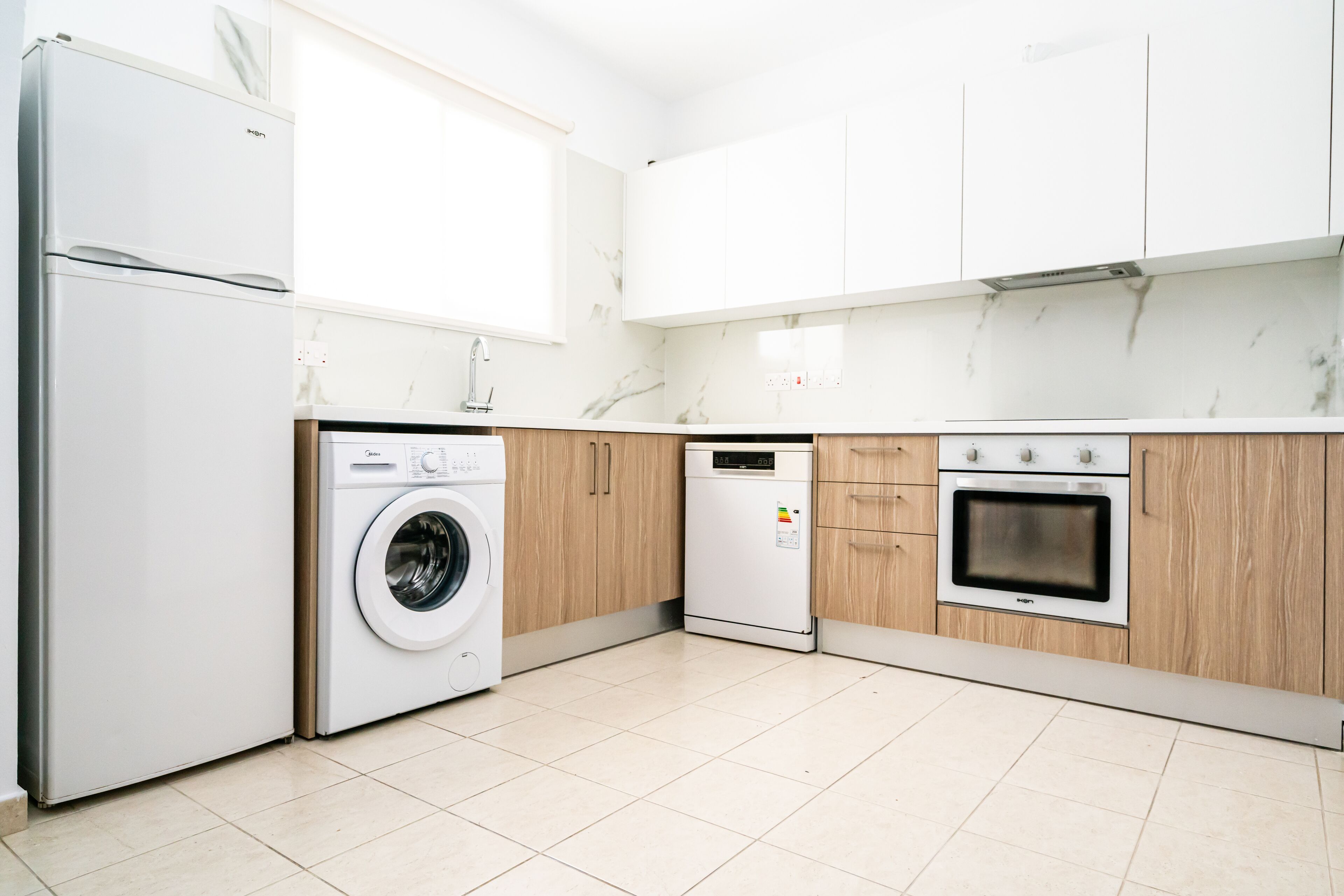 A modern kitchen with a washing machine, dishwasher, and oven.