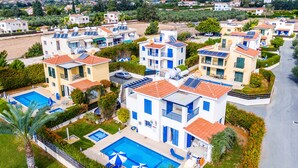 Un quartier résidentiel composé de plusieurs maisons à deux étages, chacune dotée d’une piscine et de panneaux solaires.