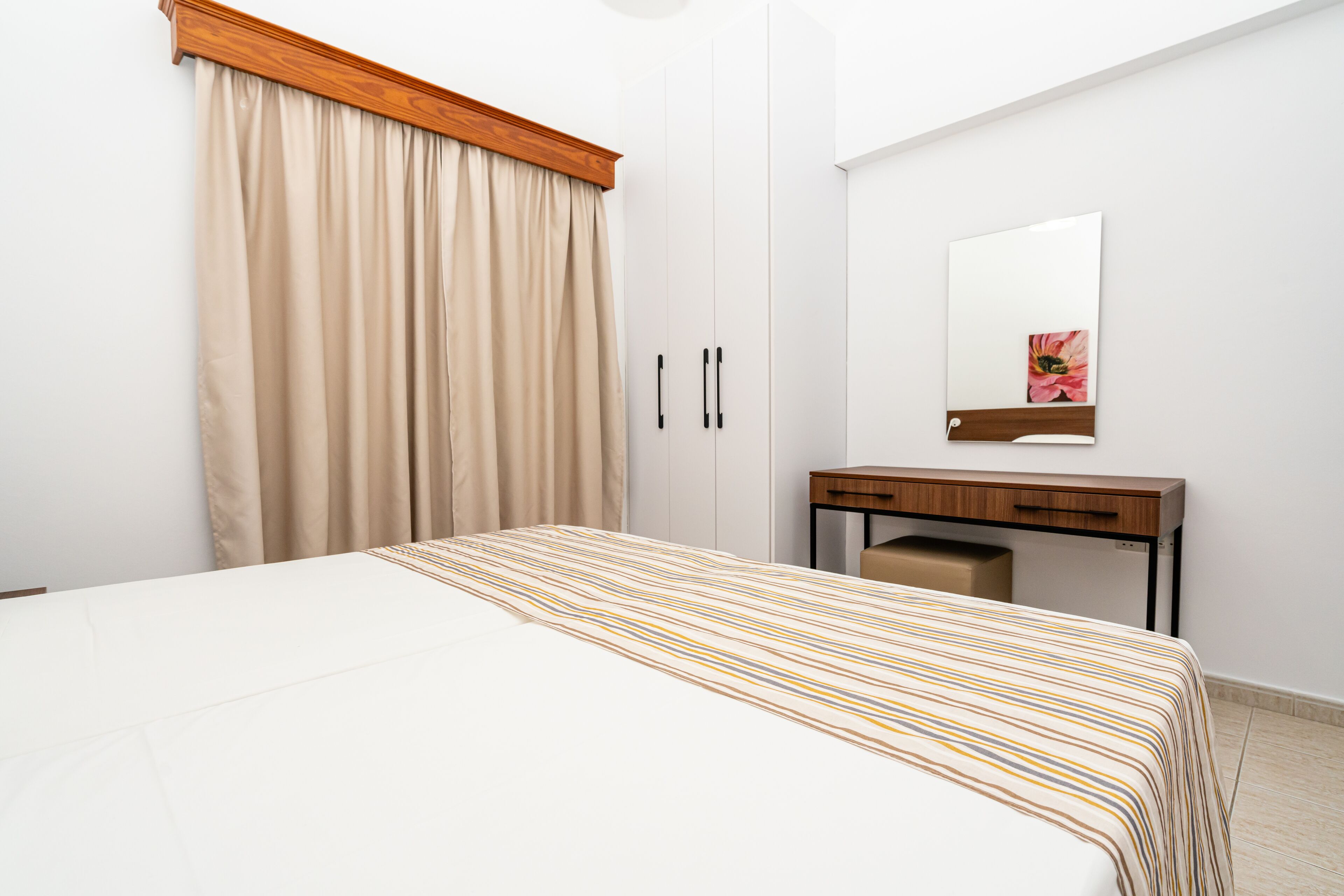 Un dormitorio con cama, un escritorio de madera, un espejo y un armario.