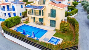 Un immeuble résidentiel doté d’une piscine, de panneaux solaires et offrant une vue sur une ville située dans une région vallonnée.
