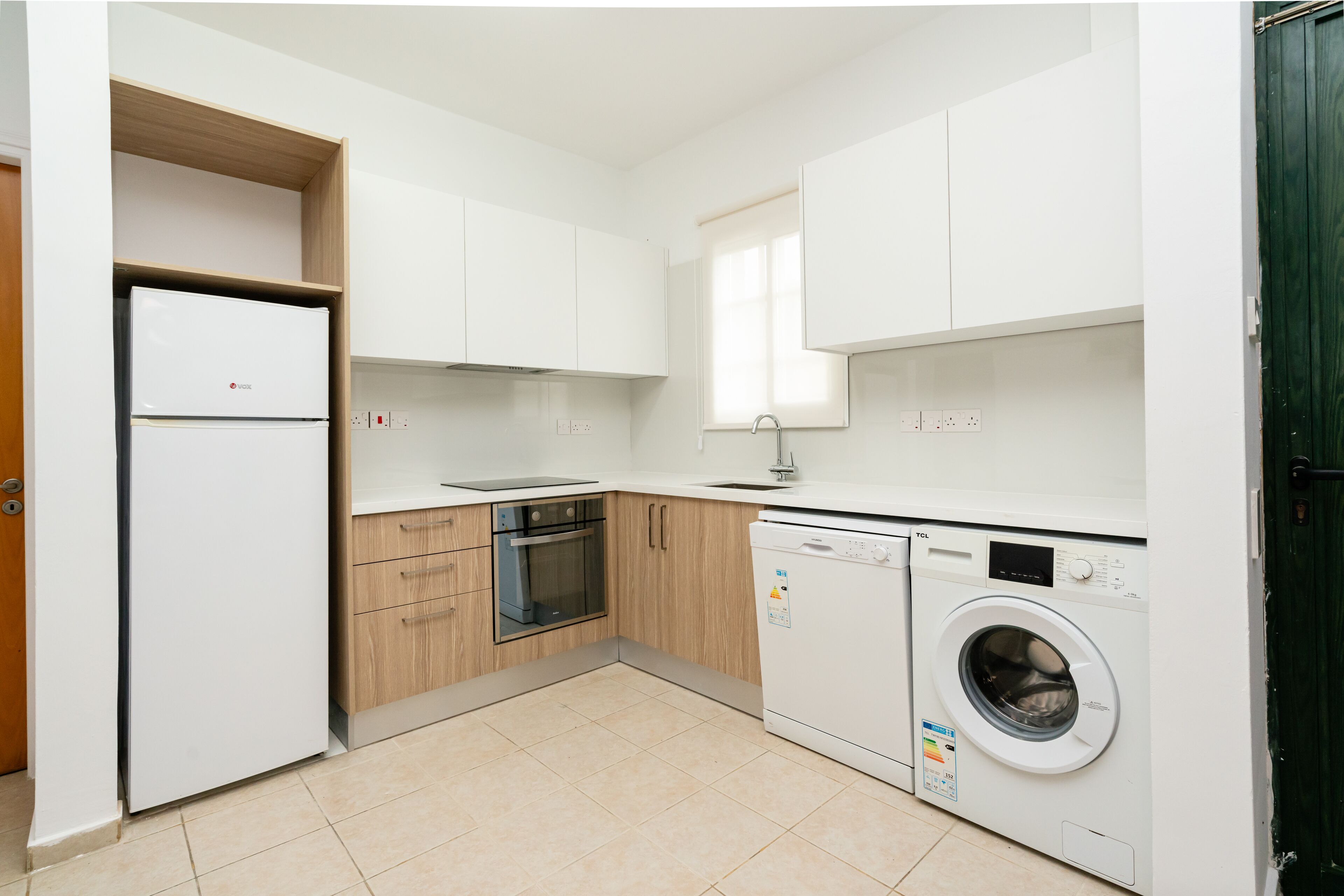 A compact kitchen with a built-in oven, a dishwasher, and a refrigerator.
