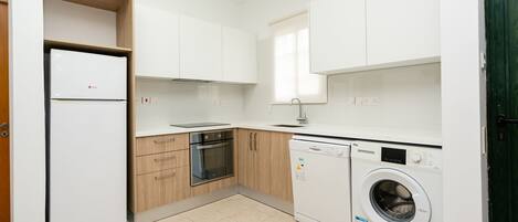 A compact kitchen with a built-in oven, a dishwasher, and a refrigerator.