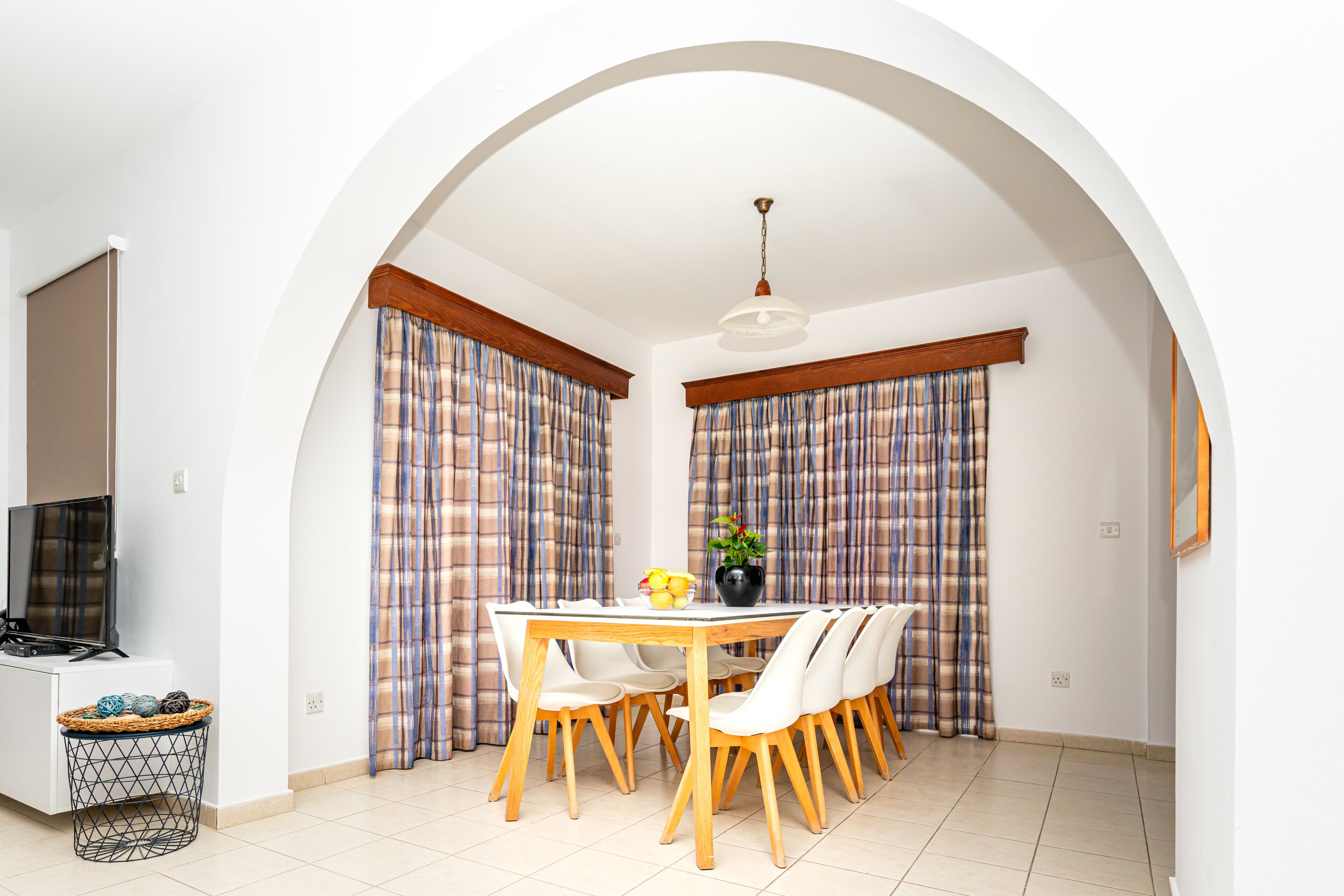 A dining area with a table and chairs, a television, and a basket of balls.