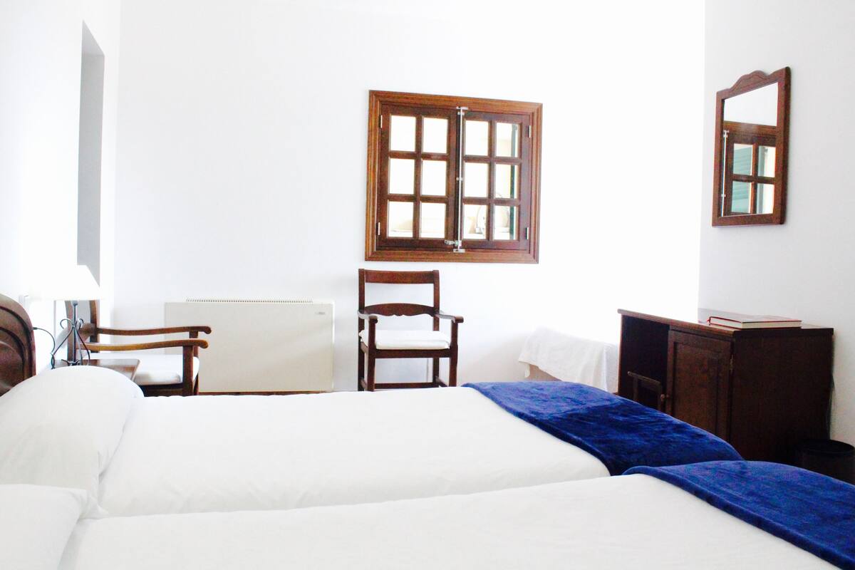 Una habitación de hotel con una cama, una silla, un escritorio y una ventana.