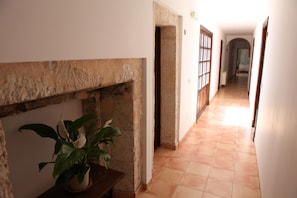 A hallway with a stone wall, a potted plant, and a tiled floor. - Hotel Can Font (Sineu)