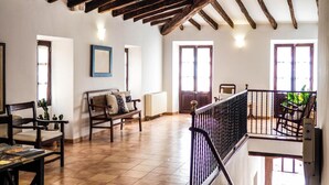 A spacious living room with wooden beams, a balcony, and a view of the outdoors. - Hotel Can Font (Sineu)
