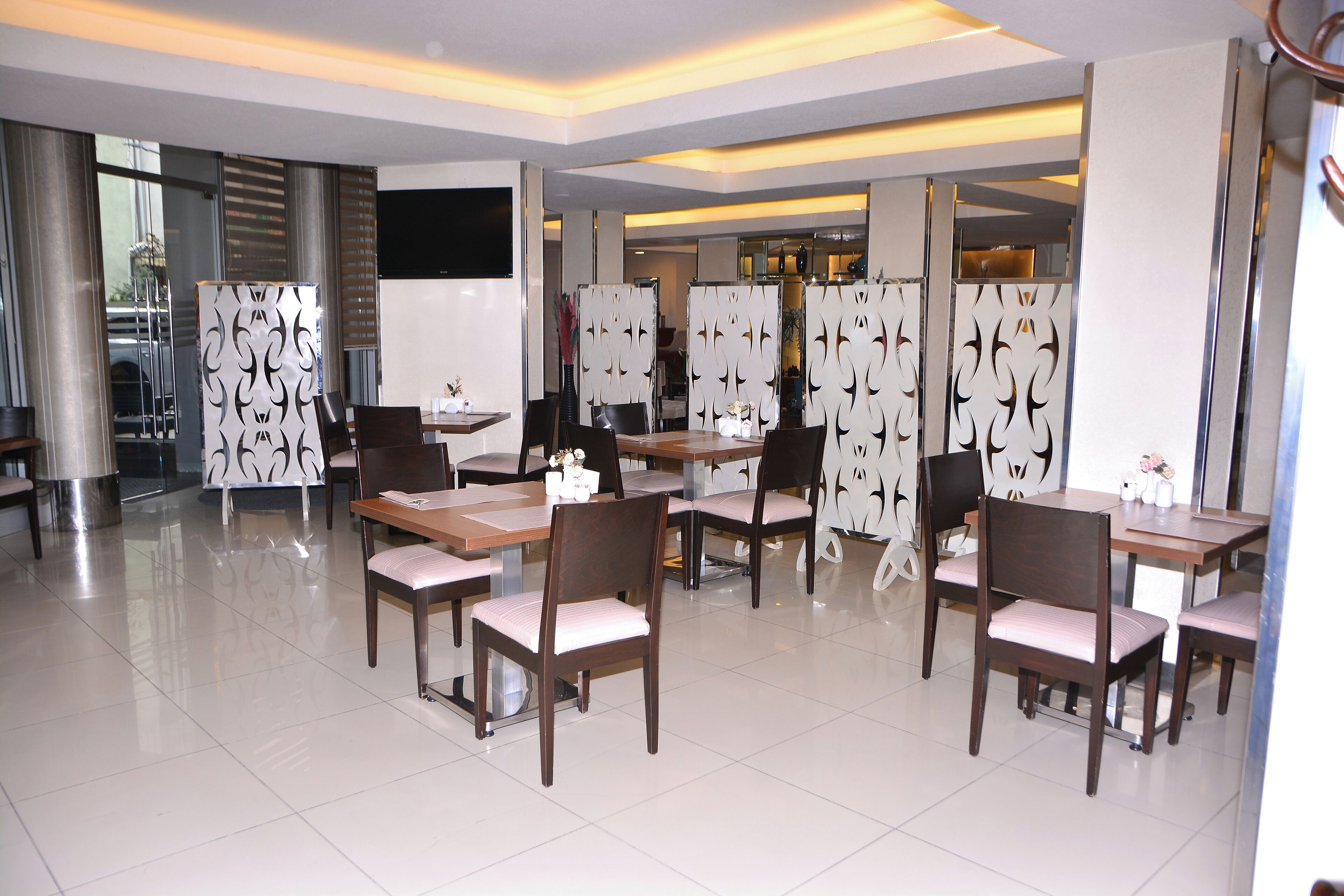 A modern dining area with tables and chairs, decorative panels, and a large window.