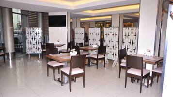 A modern dining area with tables and chairs, decorative panels, and a large window.