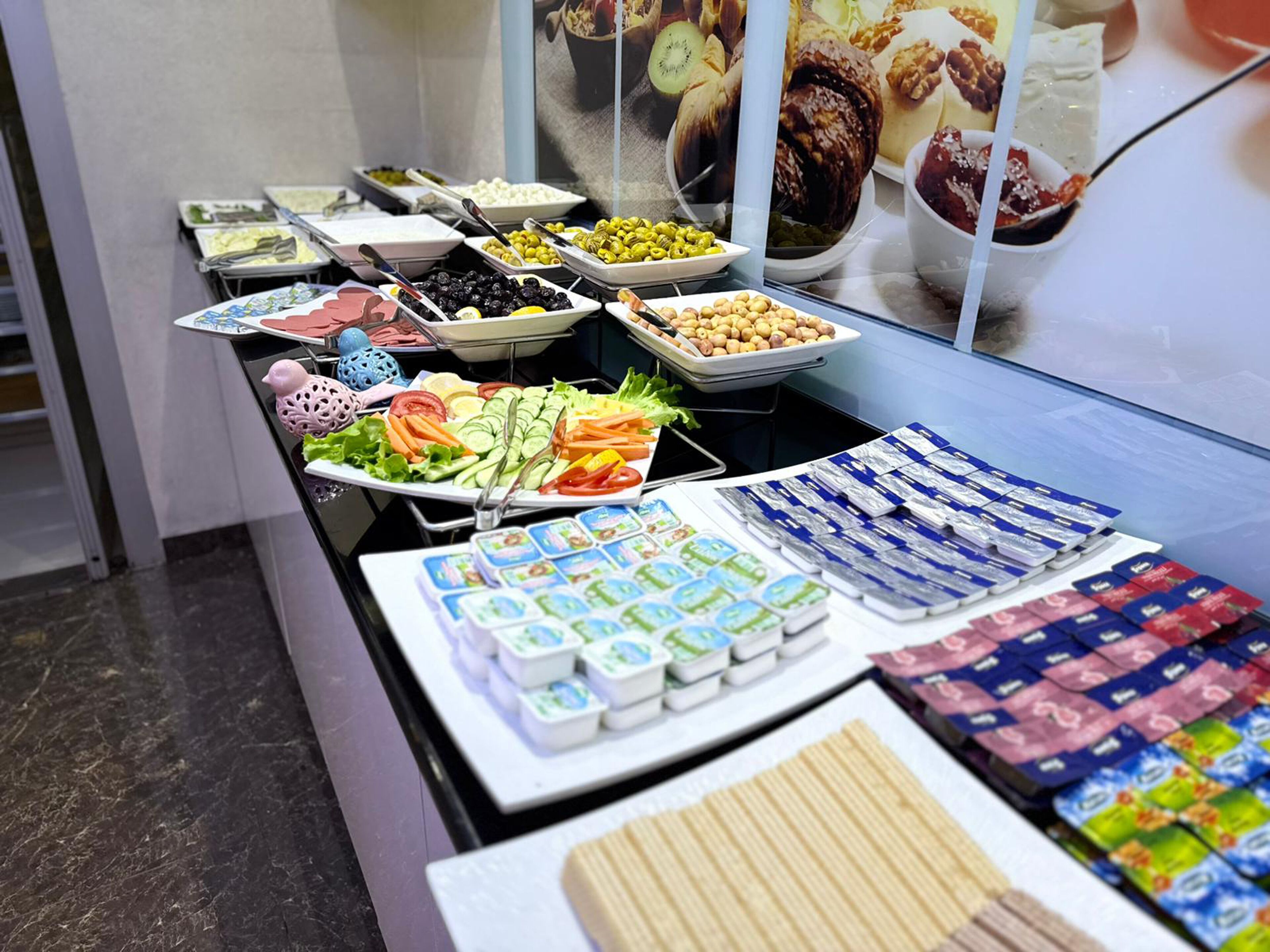 Un bufé con diversas opciones de comida, incluyendo frutas, verduras y bocadillos envasados.
