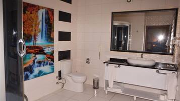A bathroom with a waterfall mural, a toilet, a sink, and a mirror.