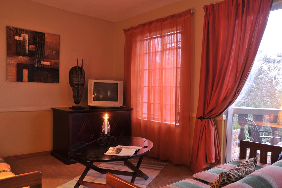 A cozy living room with a television, a table with a candle, and a sofa.