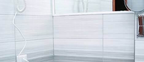 Un baño moderno con lavamanos blanco, grifo cromado y espejo. Hay una cesta con artículos de aseo sobre el mostrador.
