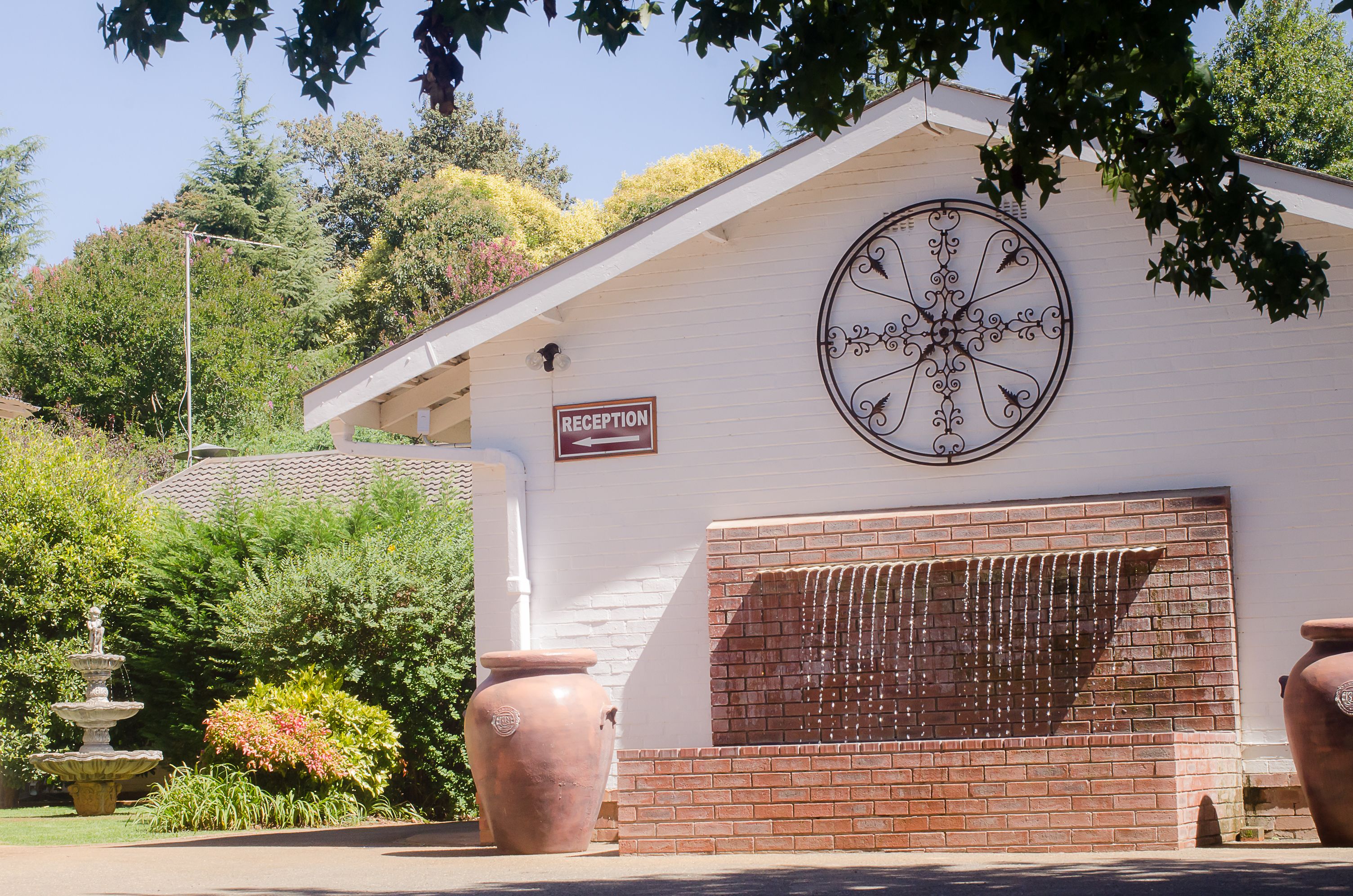 A building with a reception sign, a decorative metal piece, and a brick wall with a window.