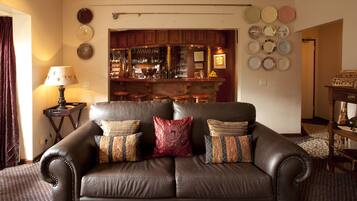 Una sala de estar con un sofá de cuero, una zona de bar con taburetes y una pared decorada con platos.