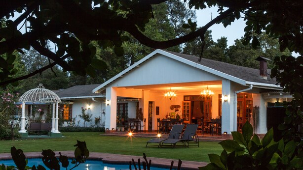 Een huis met een overdekte patio, een zwembad en een tuin.