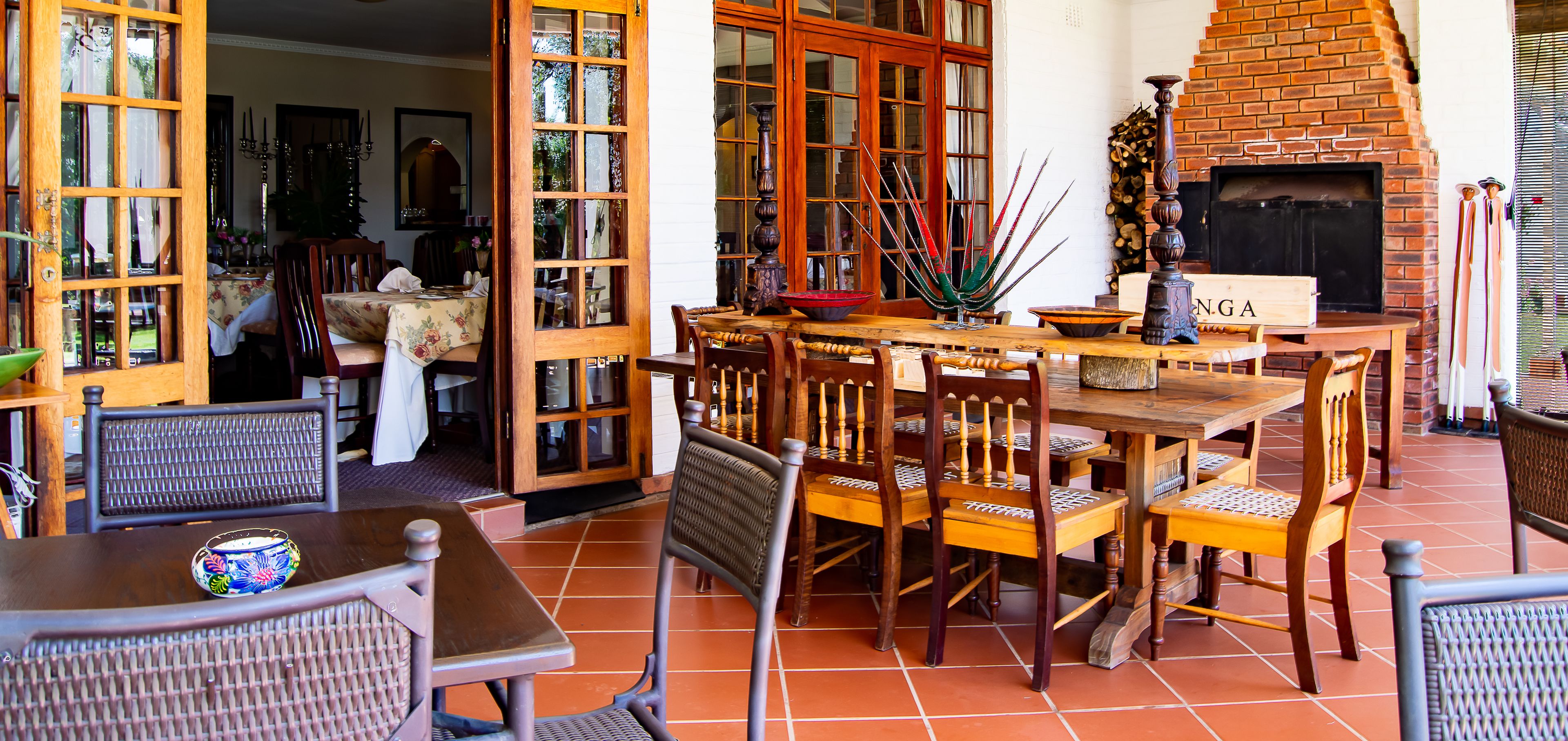 An outdoor dining area with wooden tables and chairs, a brick fireplace, and a sign reading "NGA".