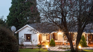 Een wit huis met een tuin, een schotelantenne en een goed verlichte buitenruimte.