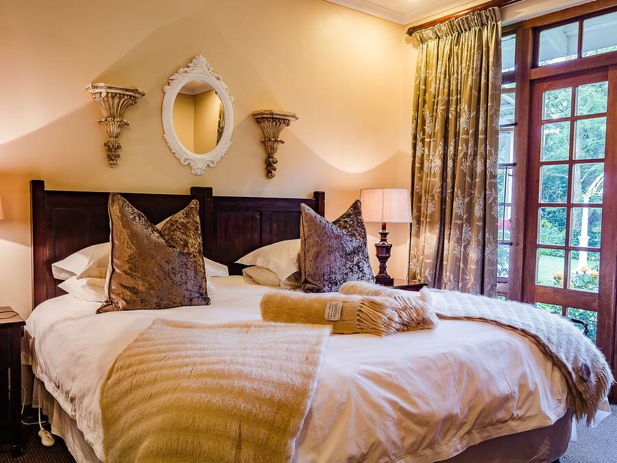 A neatly made bed with a large pillow, a bedside lamp, and a mirror on the wall.