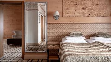 A bedroom with a large mirror, a bed with a fluffy blanket, a bedside table with a lamp, and a patterned wall.