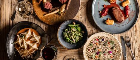 Una mesa de madera con diversos platos, entre ellos dumplings, una ensalada y un plato con carne y verduras.