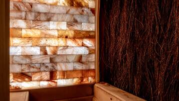Una sauna con un banco de madera, una pared de piedra con diseño de ladrillo y una pared con superficie oscura y texturizada.