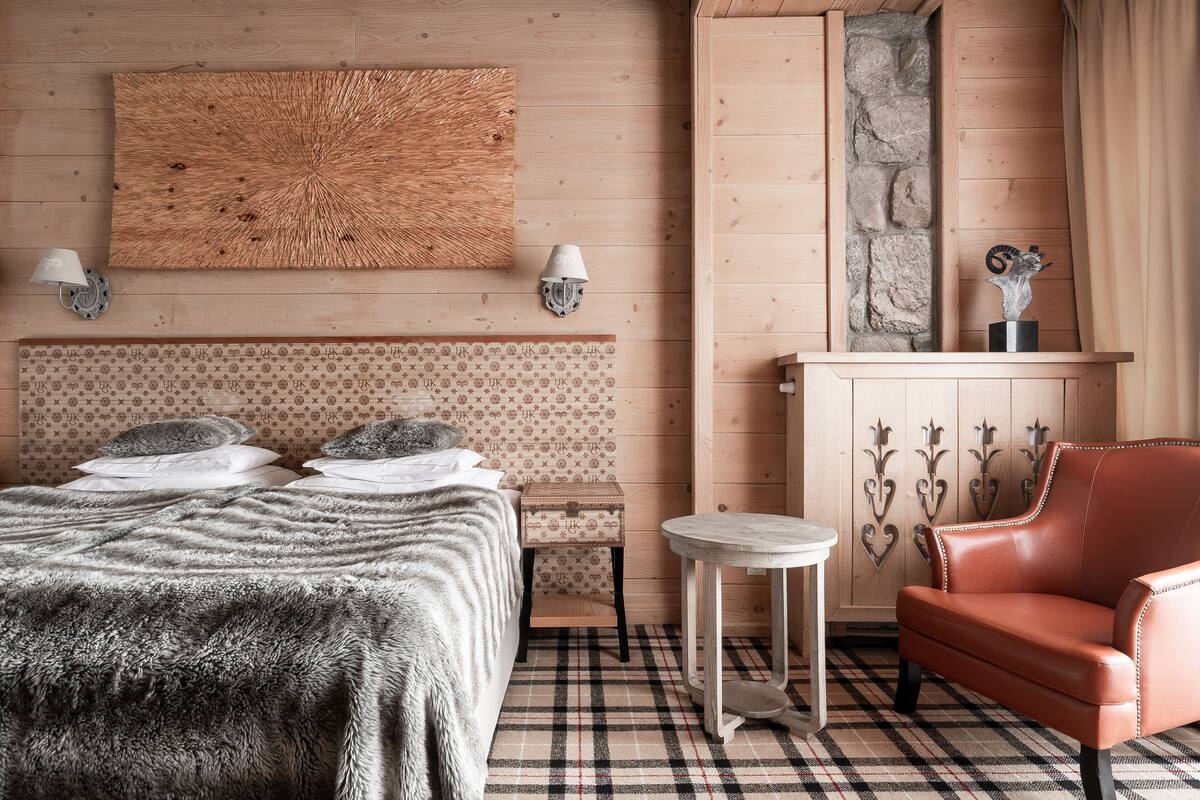 A cozy room with a bed, a small table, a leather armchair, and a decorative wall panel.