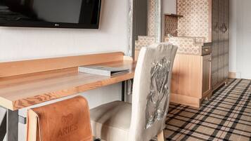 Une chambre d’hôtel moderne équipée d’une télévision à écran plat, d’un bureau en bois, d’une chaise, d’un miroir et d’une armoire.