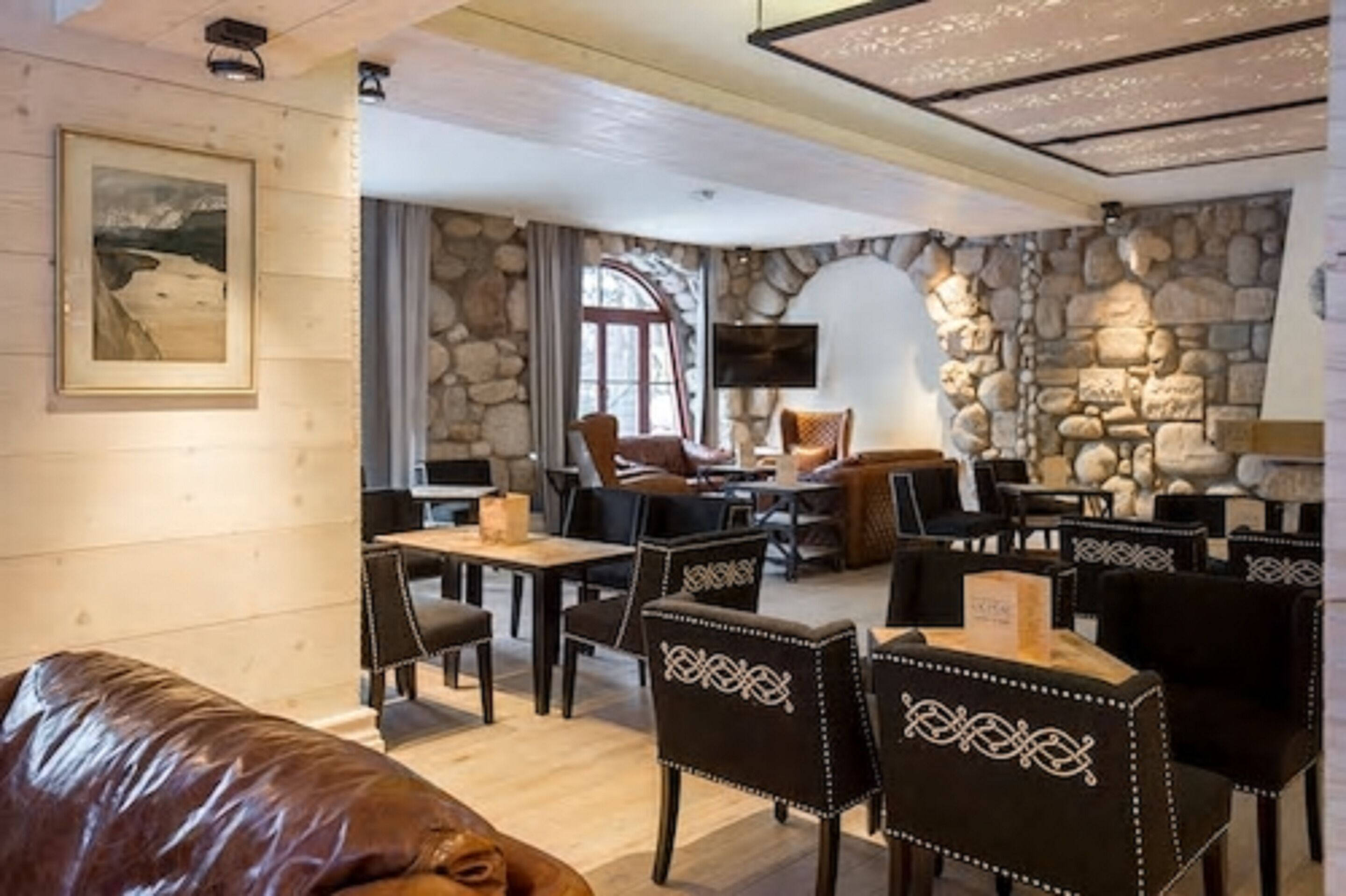 A cozy restaurant with stone walls, wooden furniture, and a fireplace.