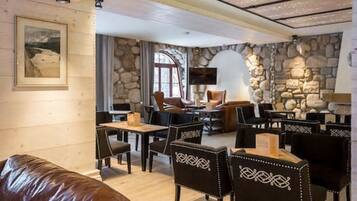 A cozy restaurant with stone walls, wooden furniture, and a fireplace.