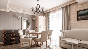 A dining area with a round table, chairs, a dresser, and a sofa. - ARIES Hotel & SPA (Zakopane)