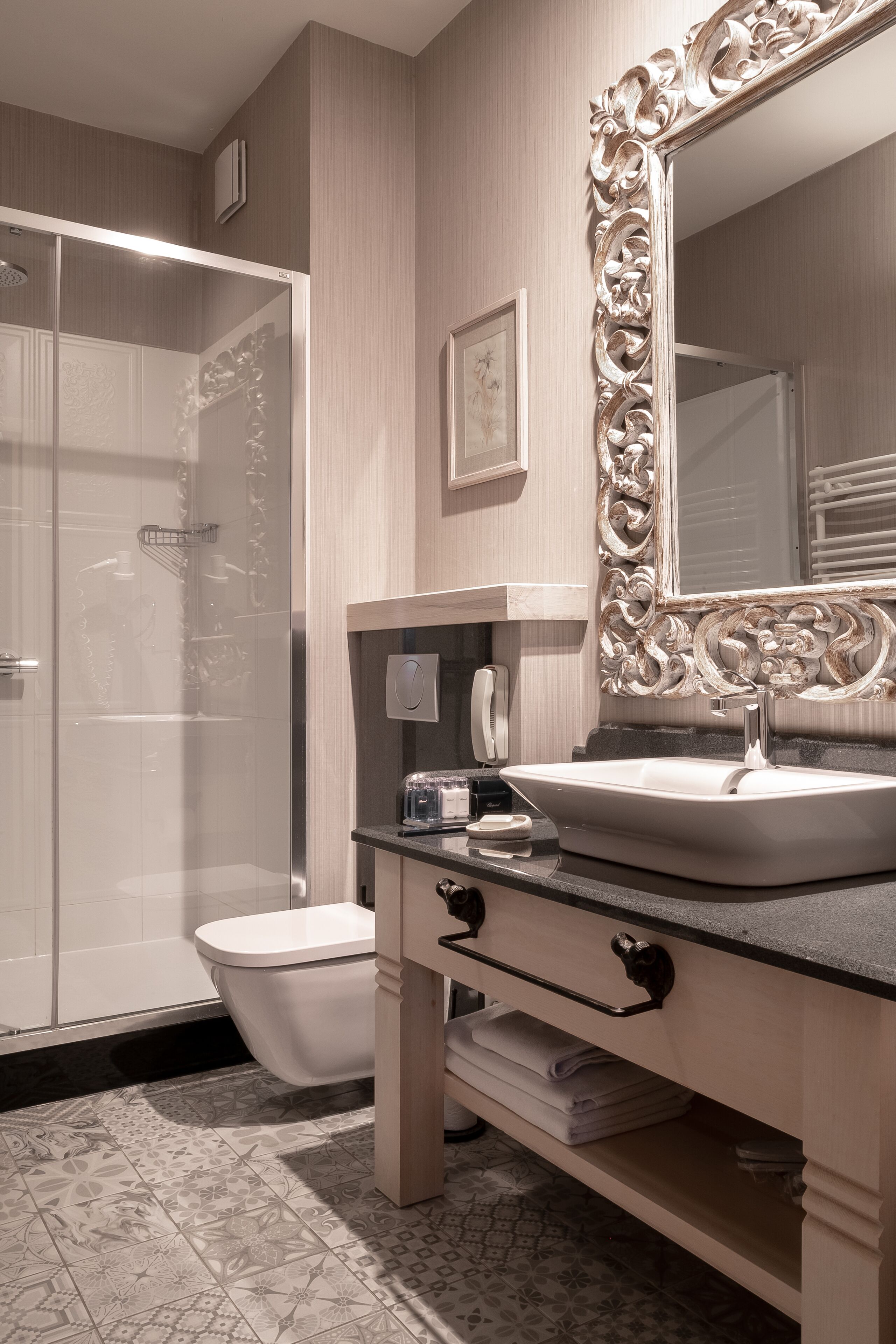 Une salle de bain avec une douche à parois de verre, un lavabo blanc et un miroir décoratif.