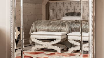 A mirrored view of a room with a patterned carpet, a fur-covered bench, and a patterned wall.