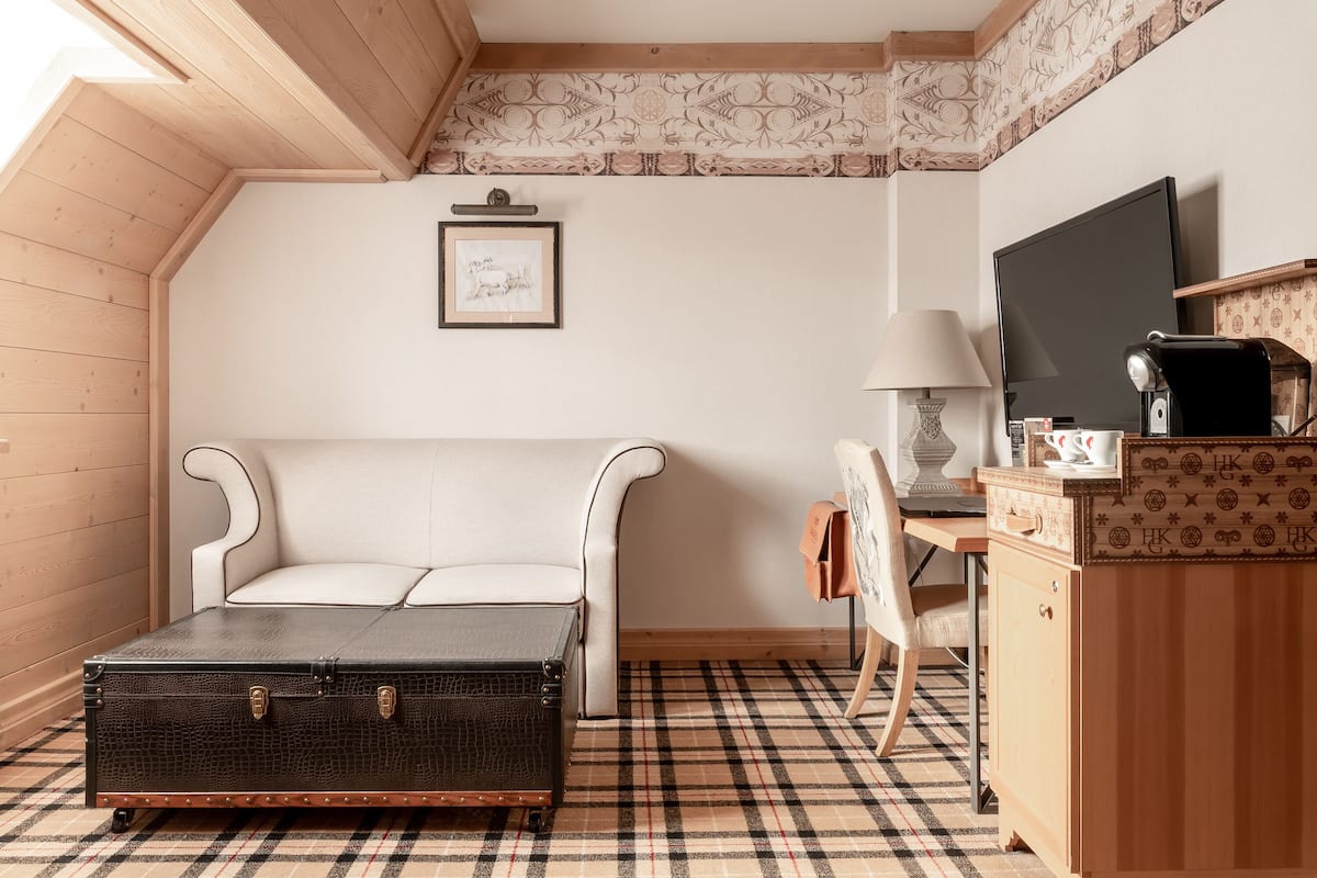 A cozy room with a bed, a desk, a lamp, and a suitcase.