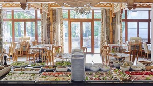 A buffet setup with various food items and a view of the outdoors through large windows. - ARIES Hotel & SPA (Zakopane)