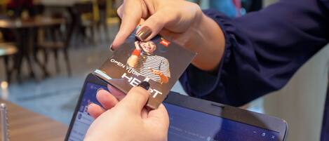 A person holding a card with a message on it, standing in front of a laptop displaying a booking interface.