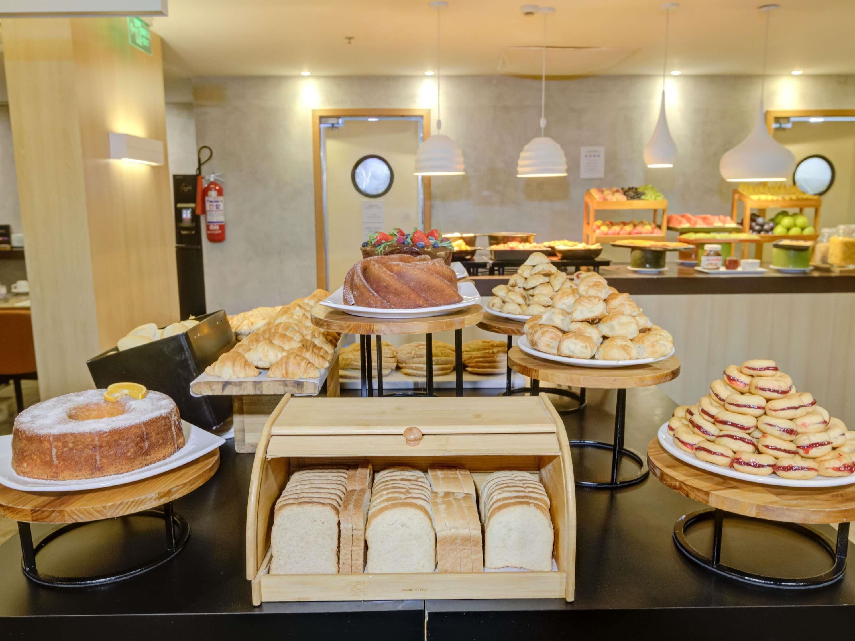 A bakery display with various baked goods, including pastries and bread, arranged on wooden stands.