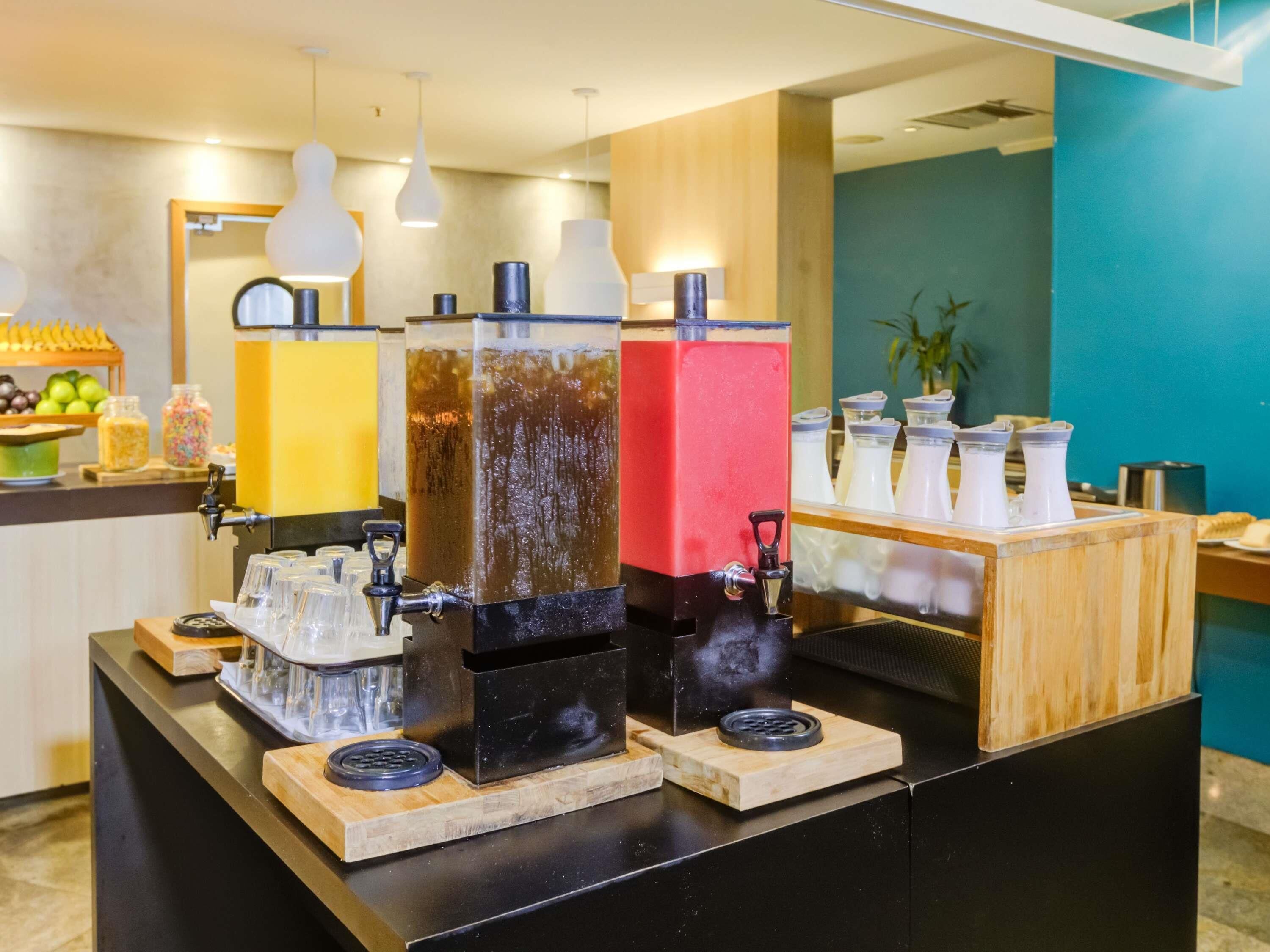 A beverage station with multiple dispensers and a counter with a fruit display.