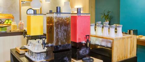 A beverage station with multiple dispensers and a counter with a fruit display.