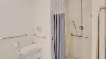 A bathroom with a toilet, a shower, and a grab bar.