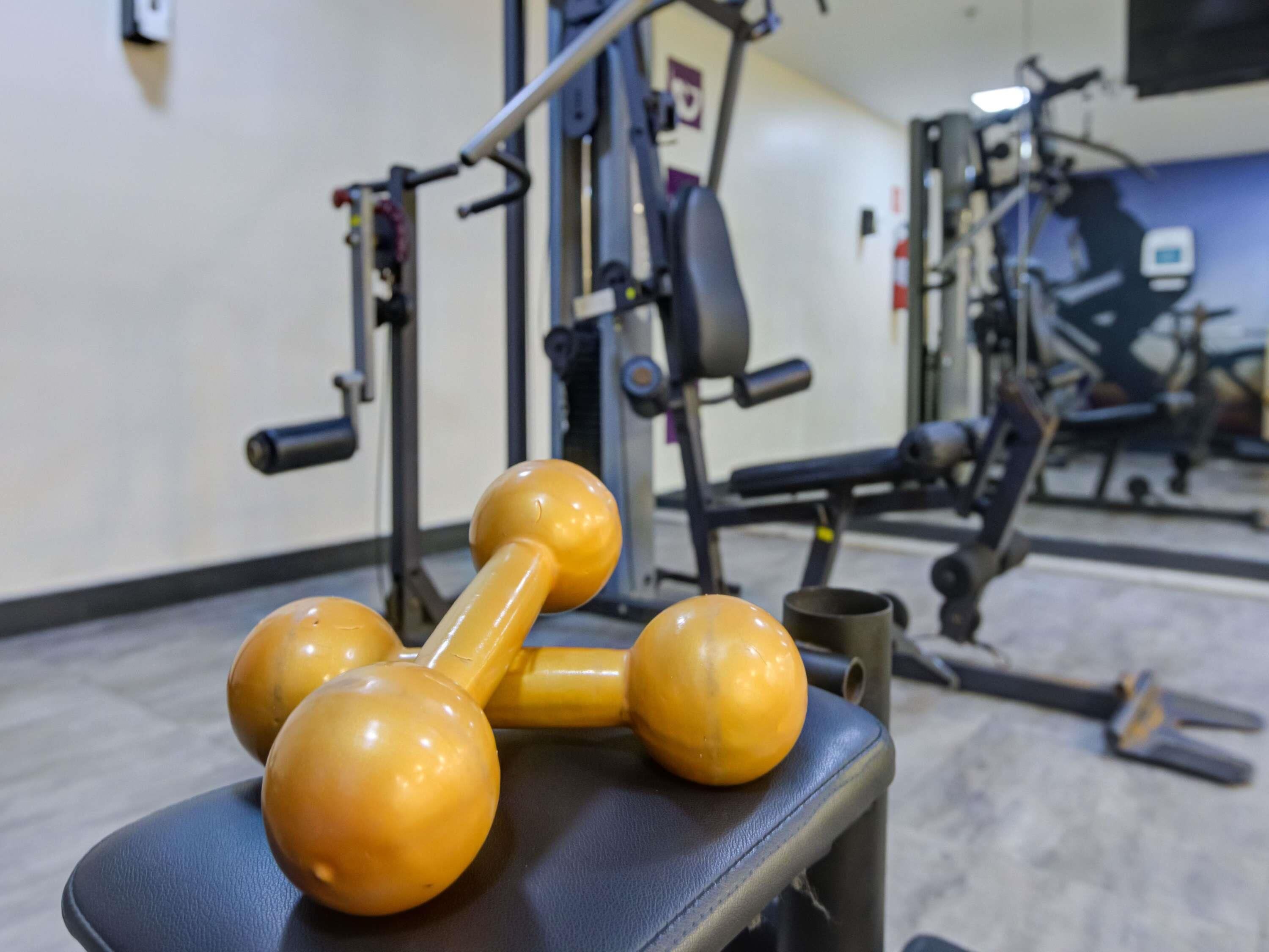 Gym equipment including dumbbells and weight machines.
