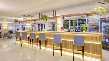 A modern bar area with a counter, bar stools, and a refrigerated display case.