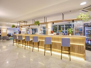 A modern bar area with a counter, bar stools, and a refrigerated display case. - ibis Rio de Janeiro Barra da Tijuca (Rio de Janeiro)