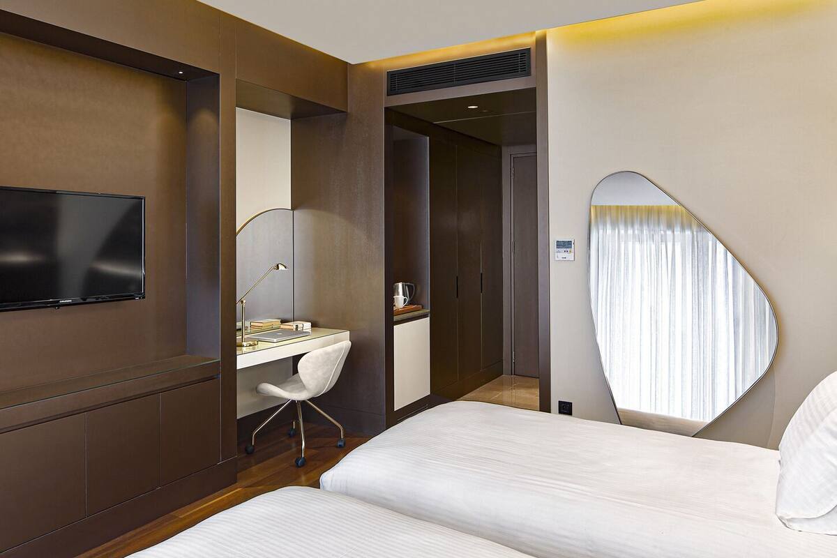 Una habitación de hotel moderna con cama, escritorio, silla y un espejo grande.