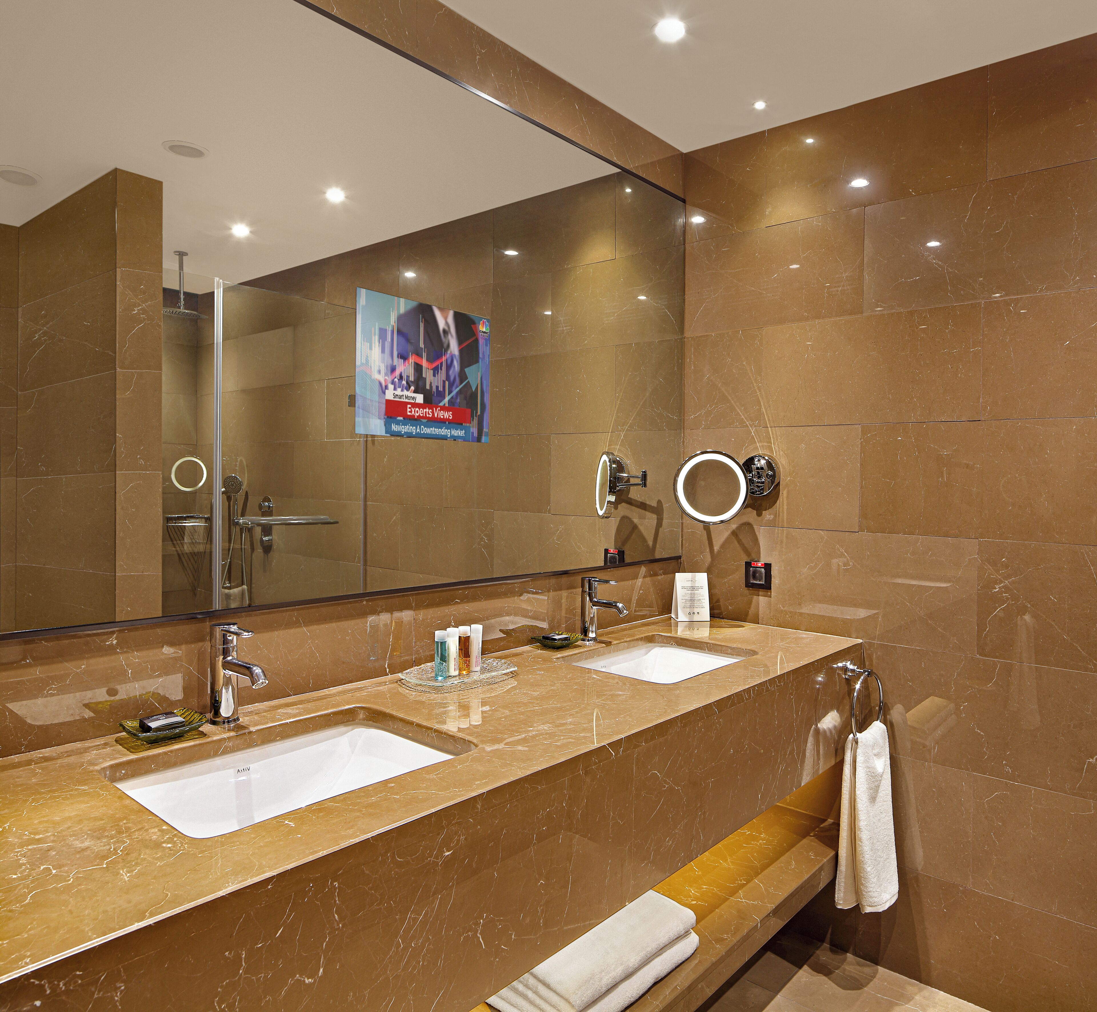 A bathroom with two sinks, a large mirror, and a towel rack.