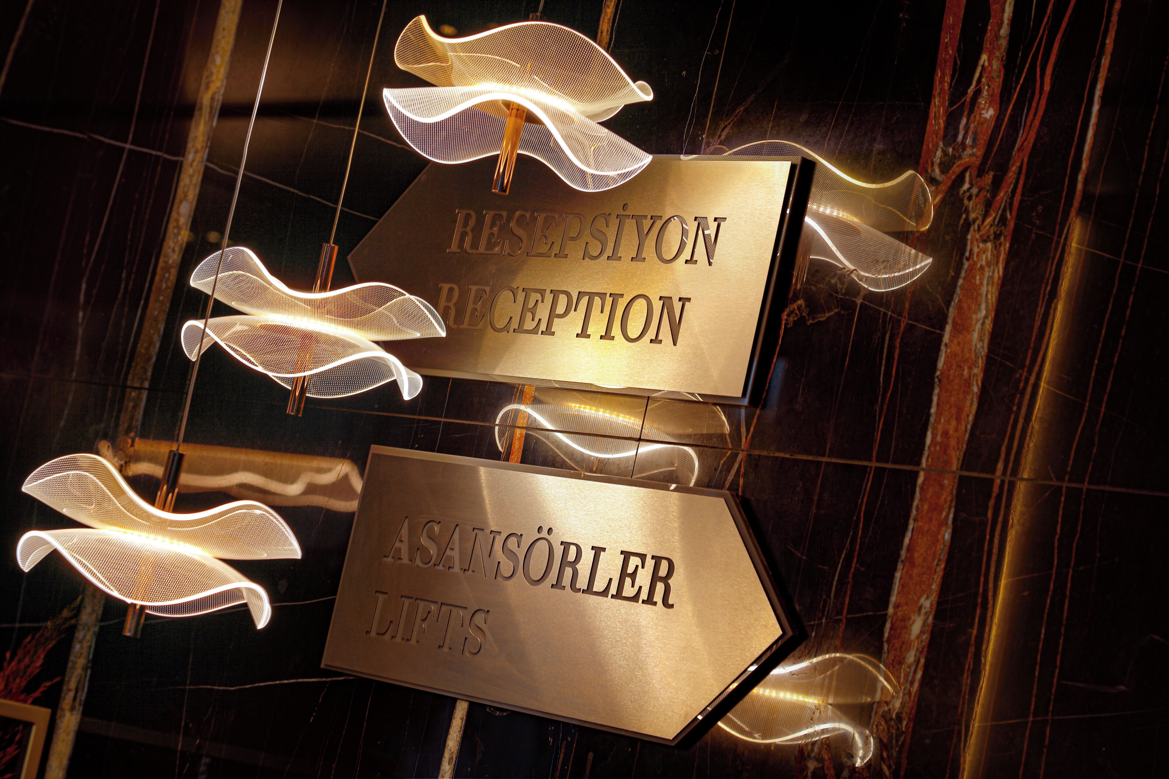 A reception sign with directional arrows and a sign for 'ASANSÖRLER GIFTS'.