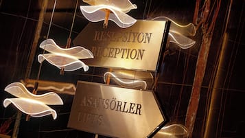 A reception sign with directional arrows and a sign for 'ASANSÖRLER GIFTS'.