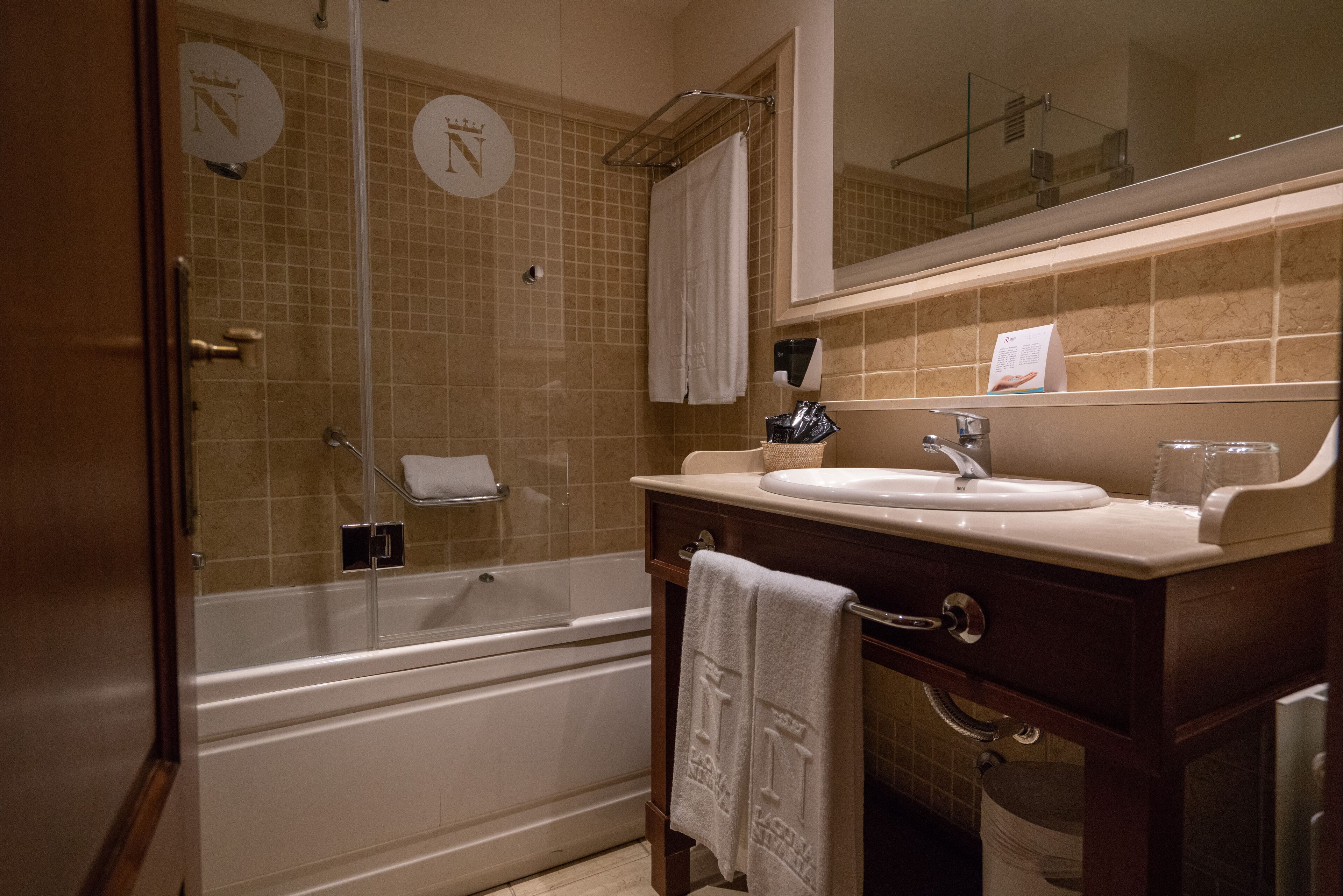 Une salle de bain équipée d’une baignoire, d’un lavabo, d’un miroir et d’un porte-serviettes.